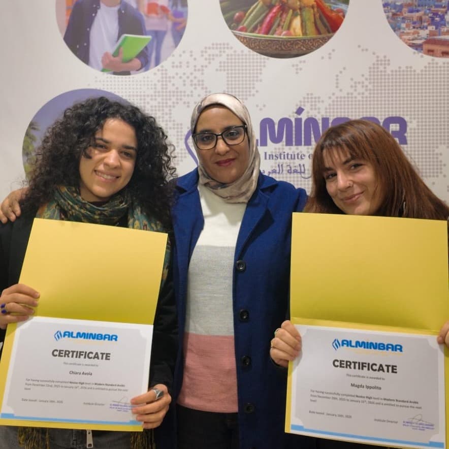 Two students holding their Al Minbar Arabic course certificates with their teacher