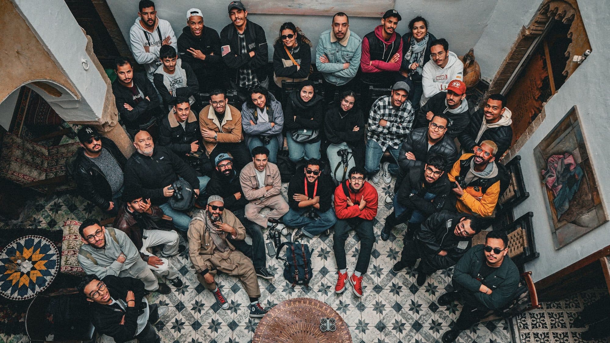 A large group of young people gathered together in a tiled Moroccan riad