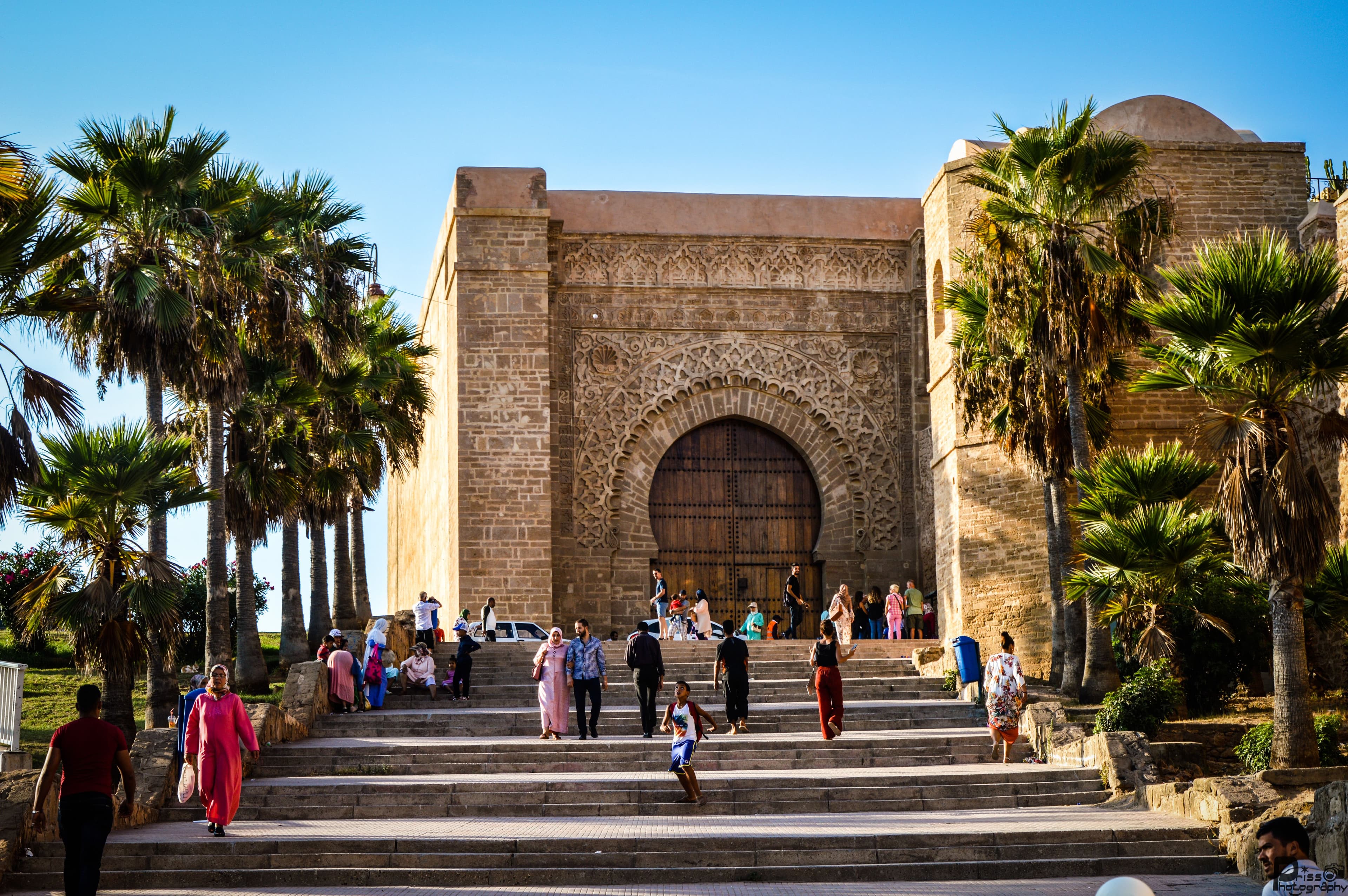 The great Almohad gate of the kasbah in Rabat, with people on the steps in golden light