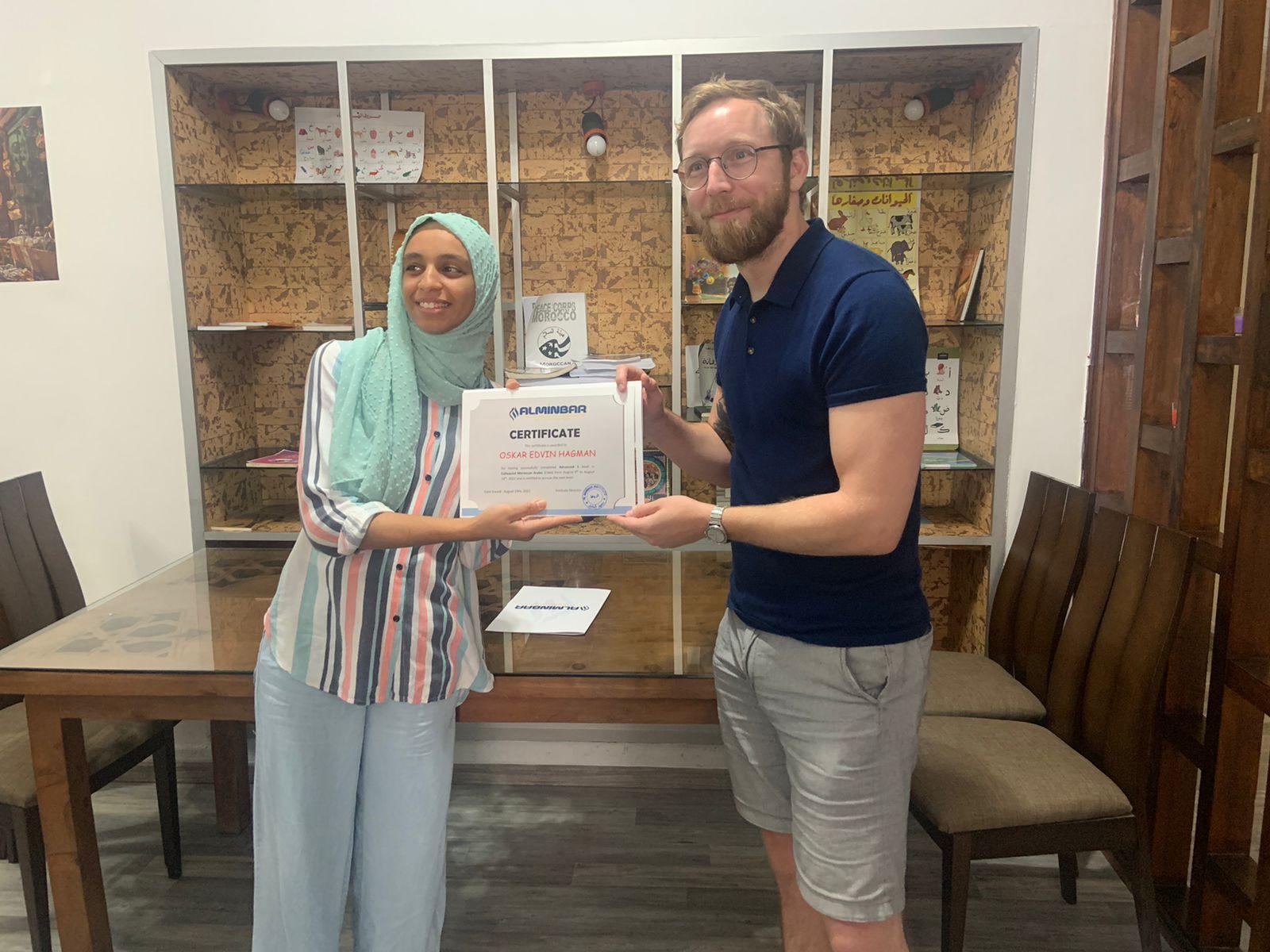 Student receiving Arabic language certification from teacher at Alminbar Institute